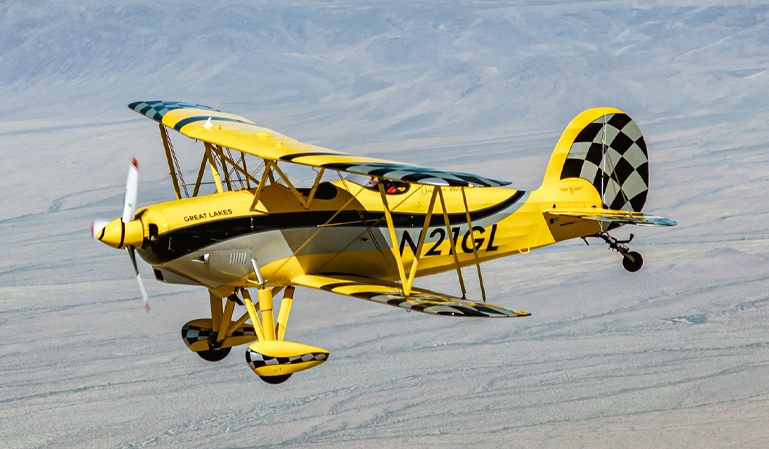 great lakes plane flying against mountains and fields