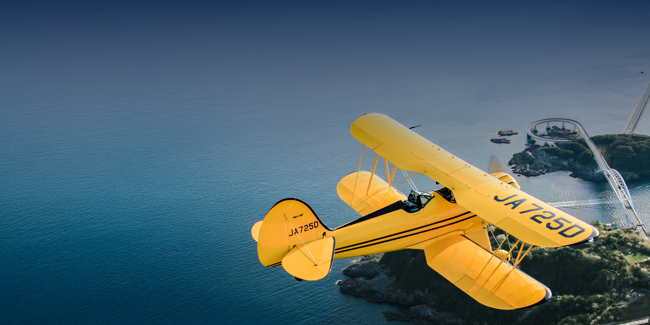 yellow plane flying above water